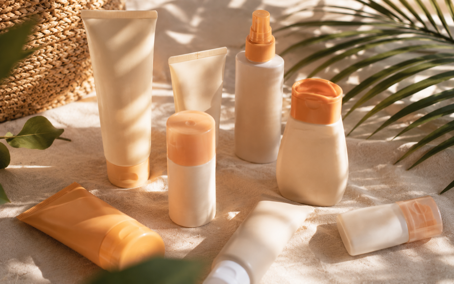 Several different sunscreen bottles gathered on a soft surface, warm morning light streaming across them