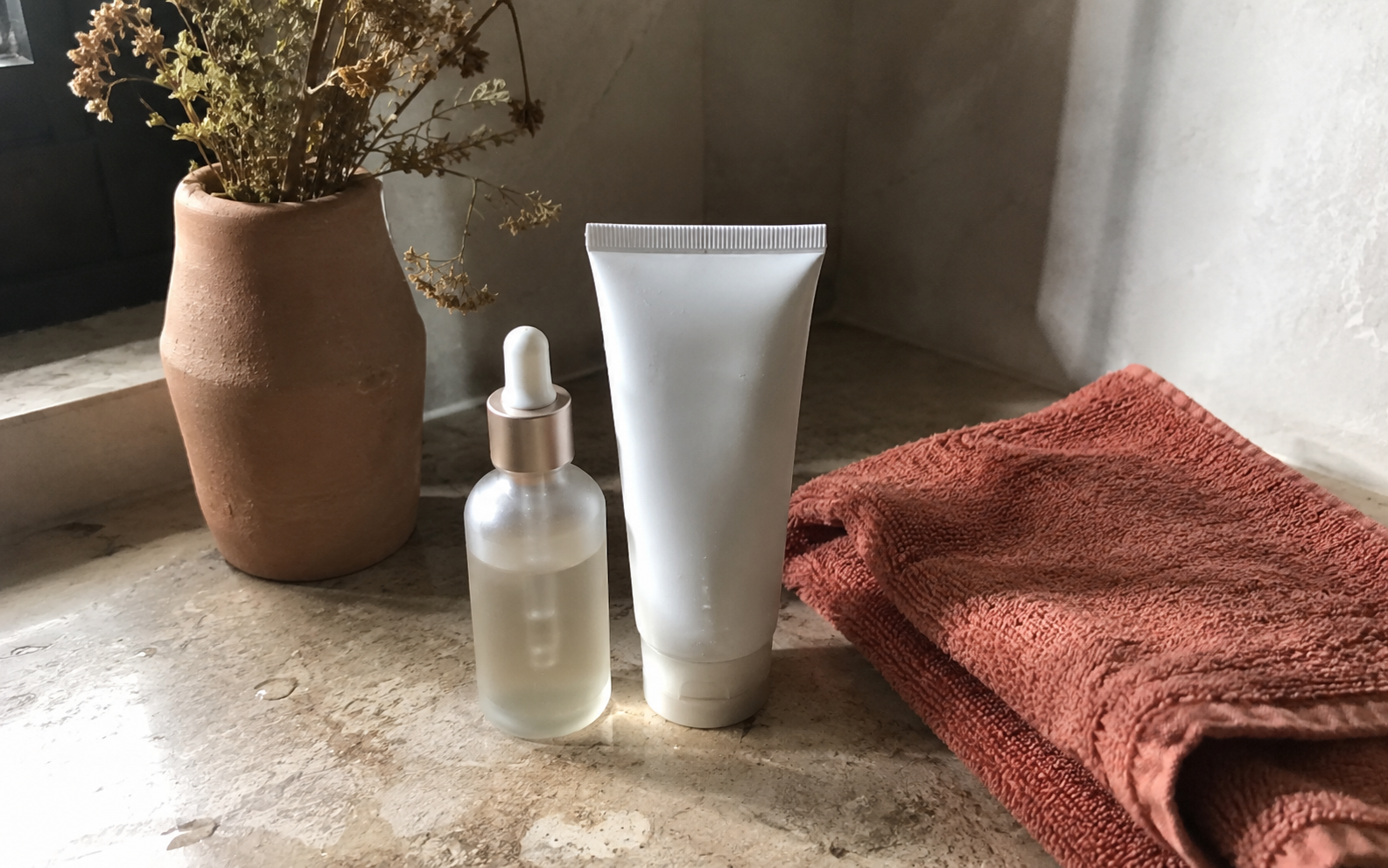 Two small skincare bottles standing together on a warm earthy surface, one for morning and one for night